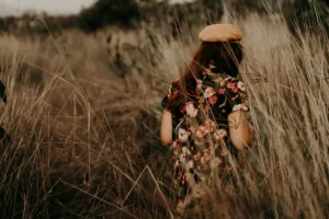 Chica caminando por un campo de trigo al atardecer, simbolizando calma y libertad tras superar la sobreexigencia